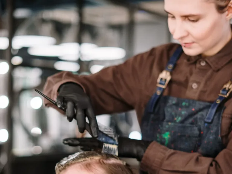 Hair stylist in an apron working with a client