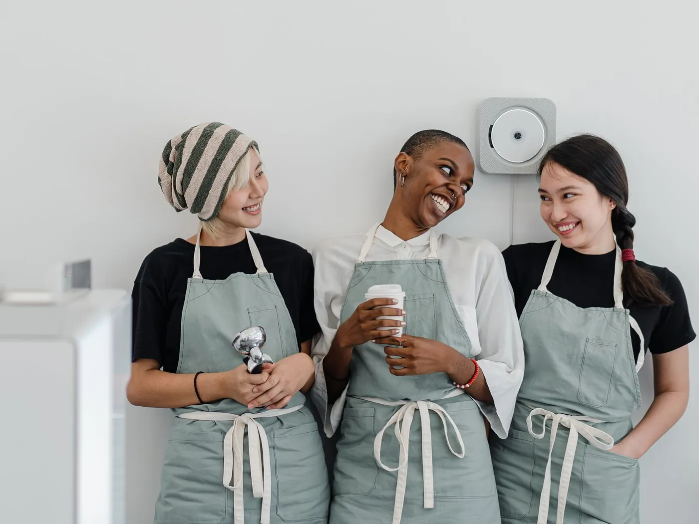 Three smiling café staff in aprons at work