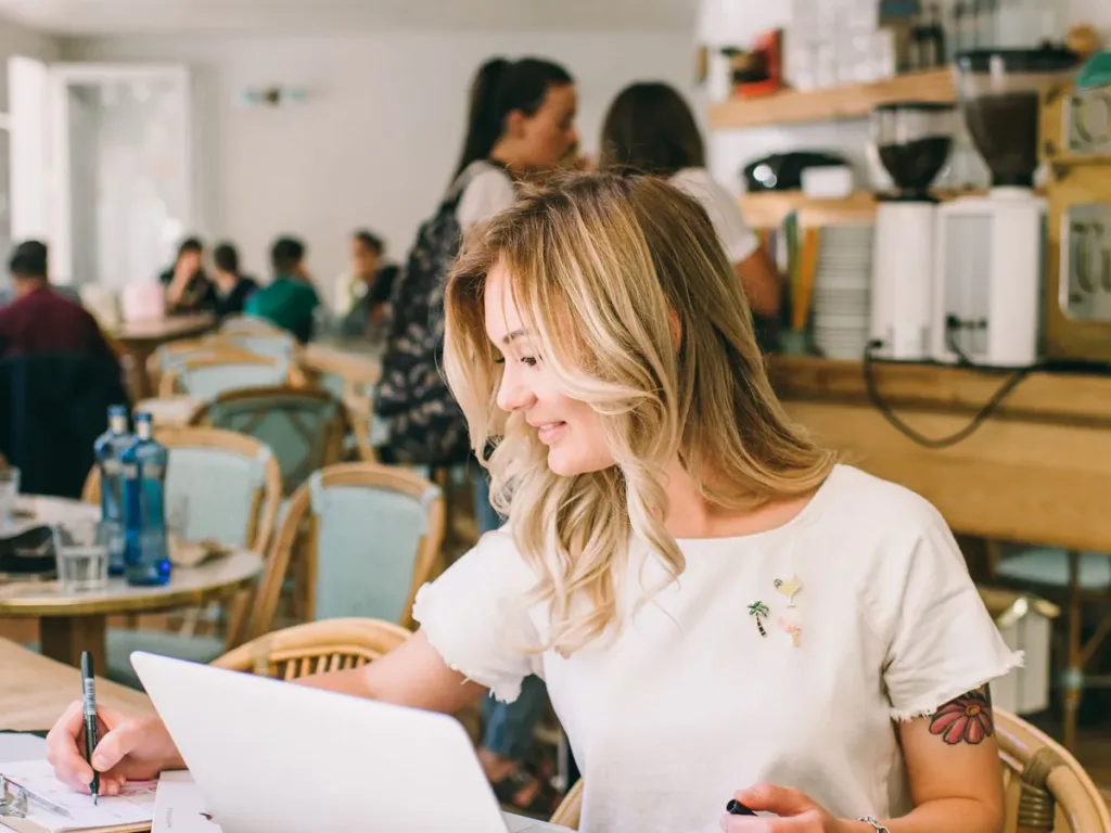 Small business owner sending a logo from a laptop in a café